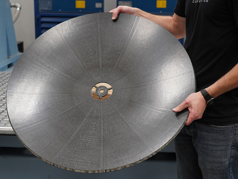 A carbon fiber reflector dish after machining Technician holding up and displaying the dish of a carbon fiber reflector after being machining
