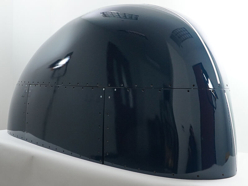 Multipart flight-qualified radome Multipart radome. This flight-qualified hardware is painted a glossy dark blue. It has a rounded shape and sits on a white table and background.